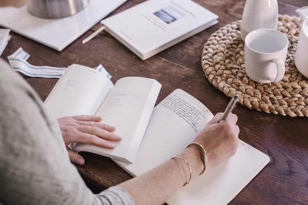 A woman writing in a notebook at her table